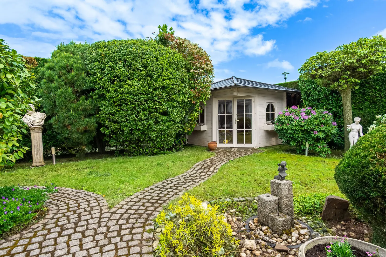 Garten mit Gartenhaus und gepflasterten Wegen
